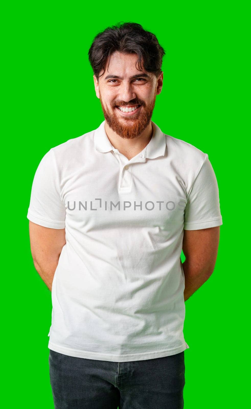 A smiling young man with a beard poses against a bright green background close up