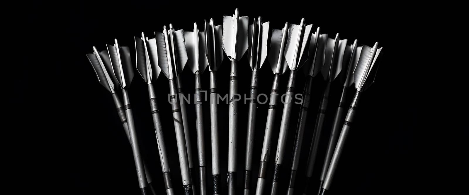 The image portrays a striking arrangement of arrows fanned out against a stark black background, creating a dramatic contrast that accentuates their sleek forms. The arrows' metallic points gleam with precision, evoking a sense of readiness and unity, as if poised for a collective purpose, exuding an aura of focus and determination.