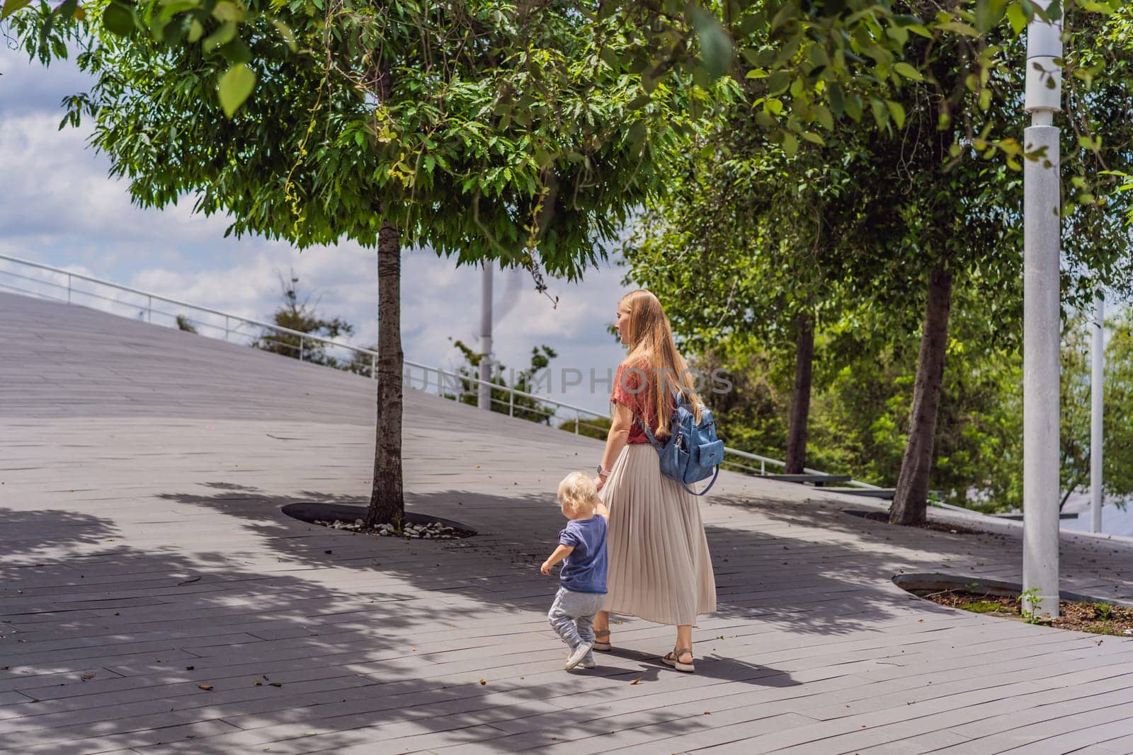 Mother with her toddler son walking in the park. Family bonding, outdoor exploration, and parenting concept.