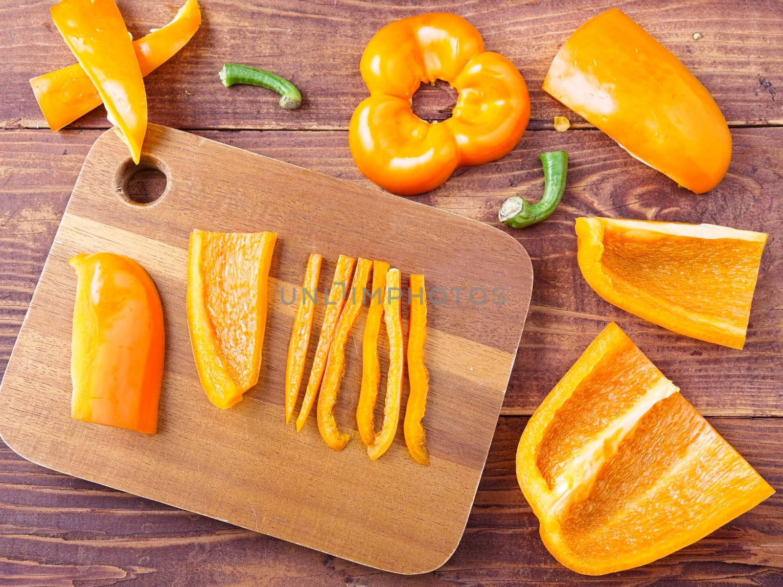A flat lay photo of chopped up orange bell peppers on a cutting board.