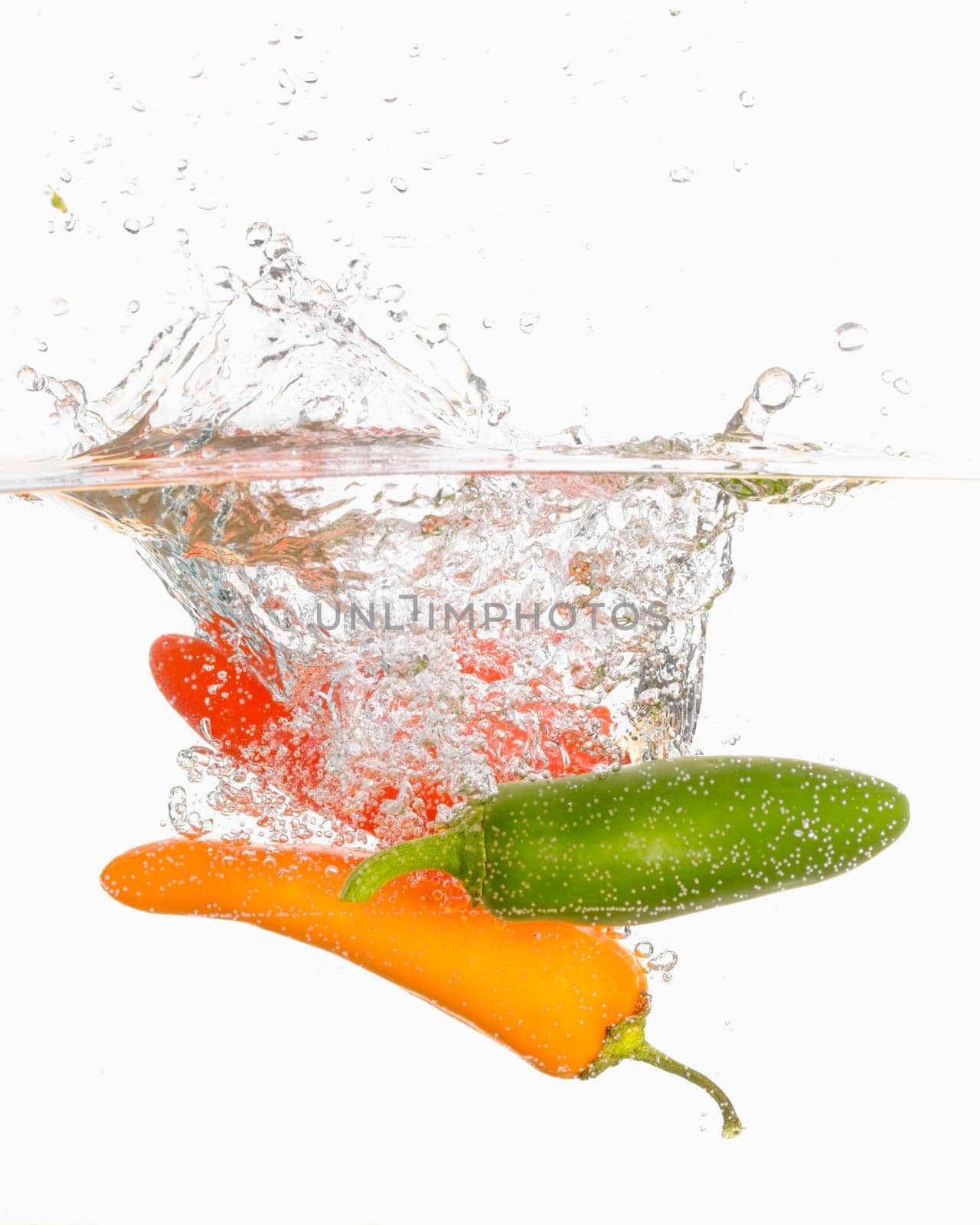 An abstract photo of three sweet peppers dropped into clear water.