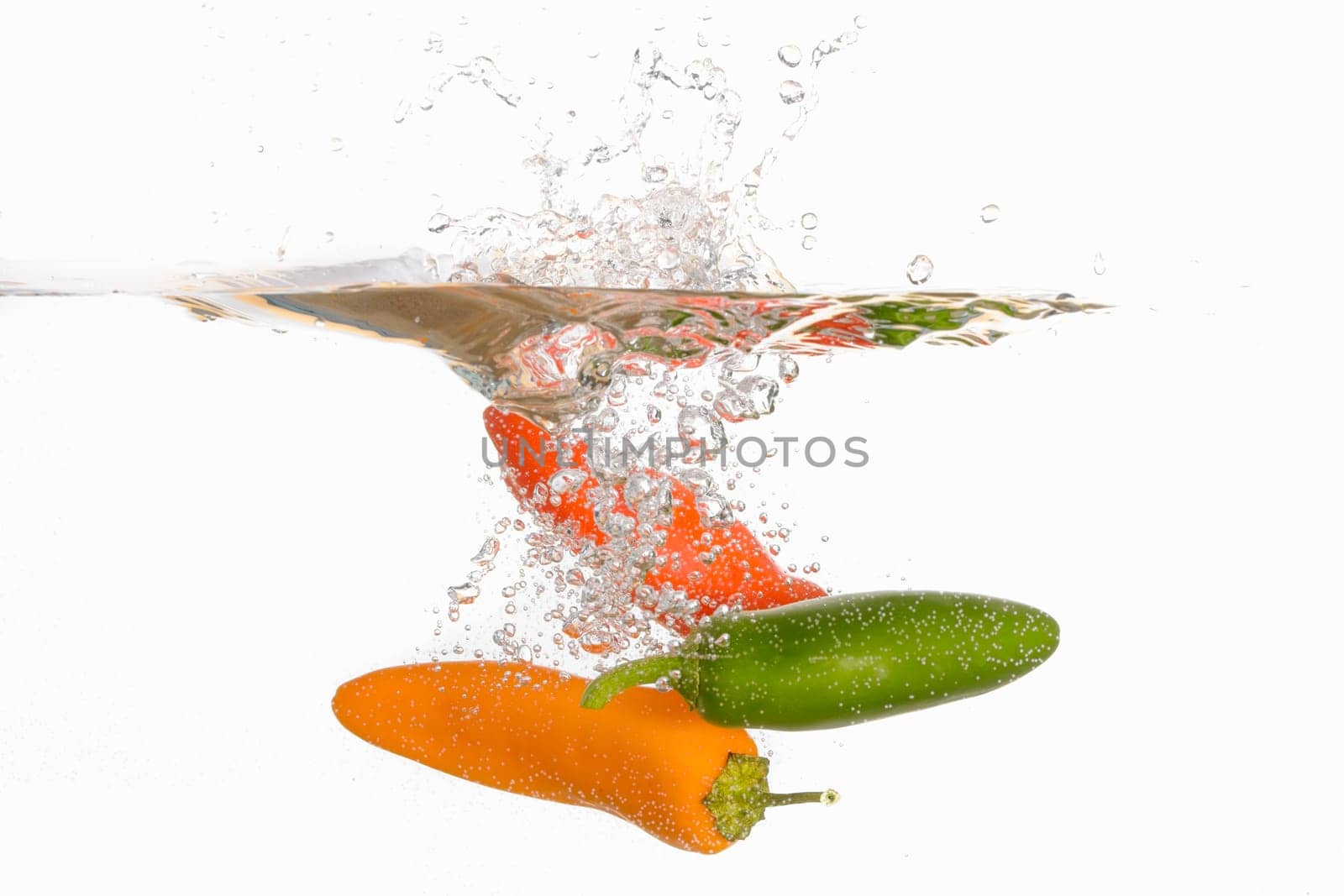 An abstract photo of three sweet peppers dropped into clear water.