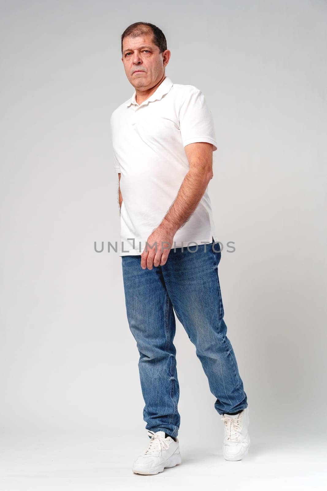 A middle-aged man poses confidently in casual attire against a neutral background in studio