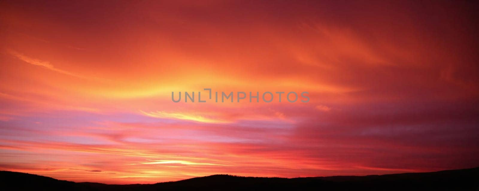 The sky is filled with stunning orange and purple hues as the sun sets behind the hills, creating a breathtaking view that captures the beauty of nature at dusk.