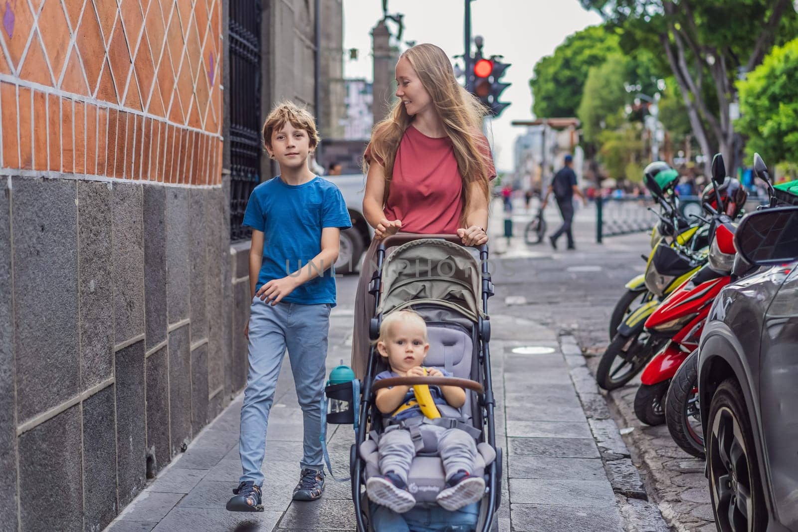 Mother tourist with her toddler and teenage sons walking through the colorful colonial streets of Puebla, Mexico. Travel, cultural exploration, and vibrant architecture concept.