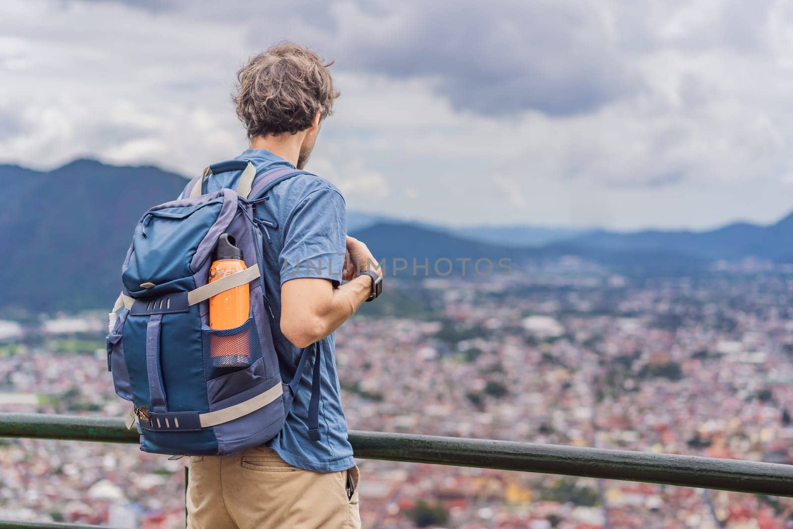 Male tourist in front of the panoramic view of Orizaba from Cerro del Borrego, Mexico. Travel, scenic landscape, and adventure concept.