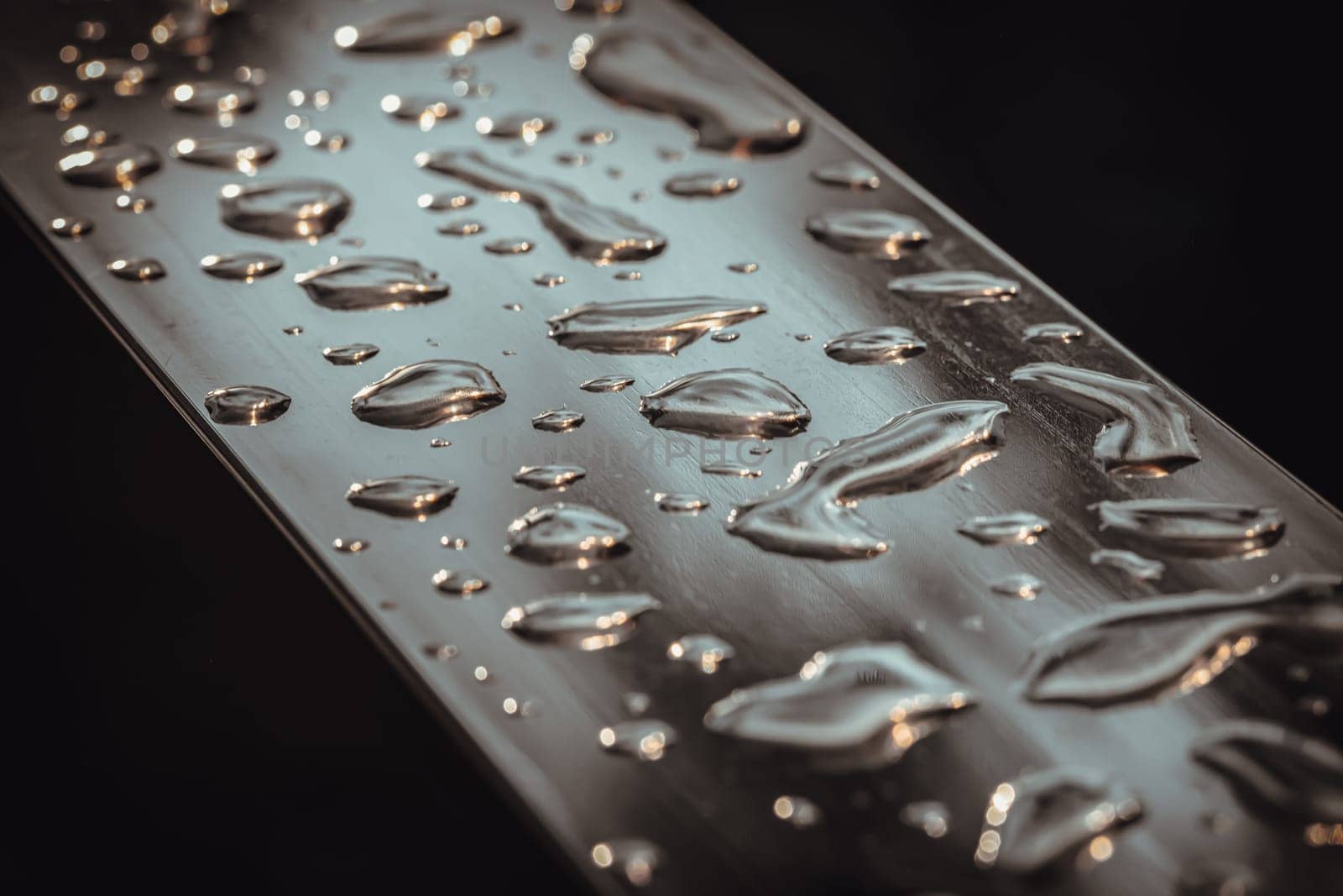 Detail of Water droplets caused by rain perched on the metallic surface. Rain water drops on a stainless steel handle, Natural Pattern of dew drops or raindrops on silver metal background for wallpaper poster and banner design, Selective focus.
