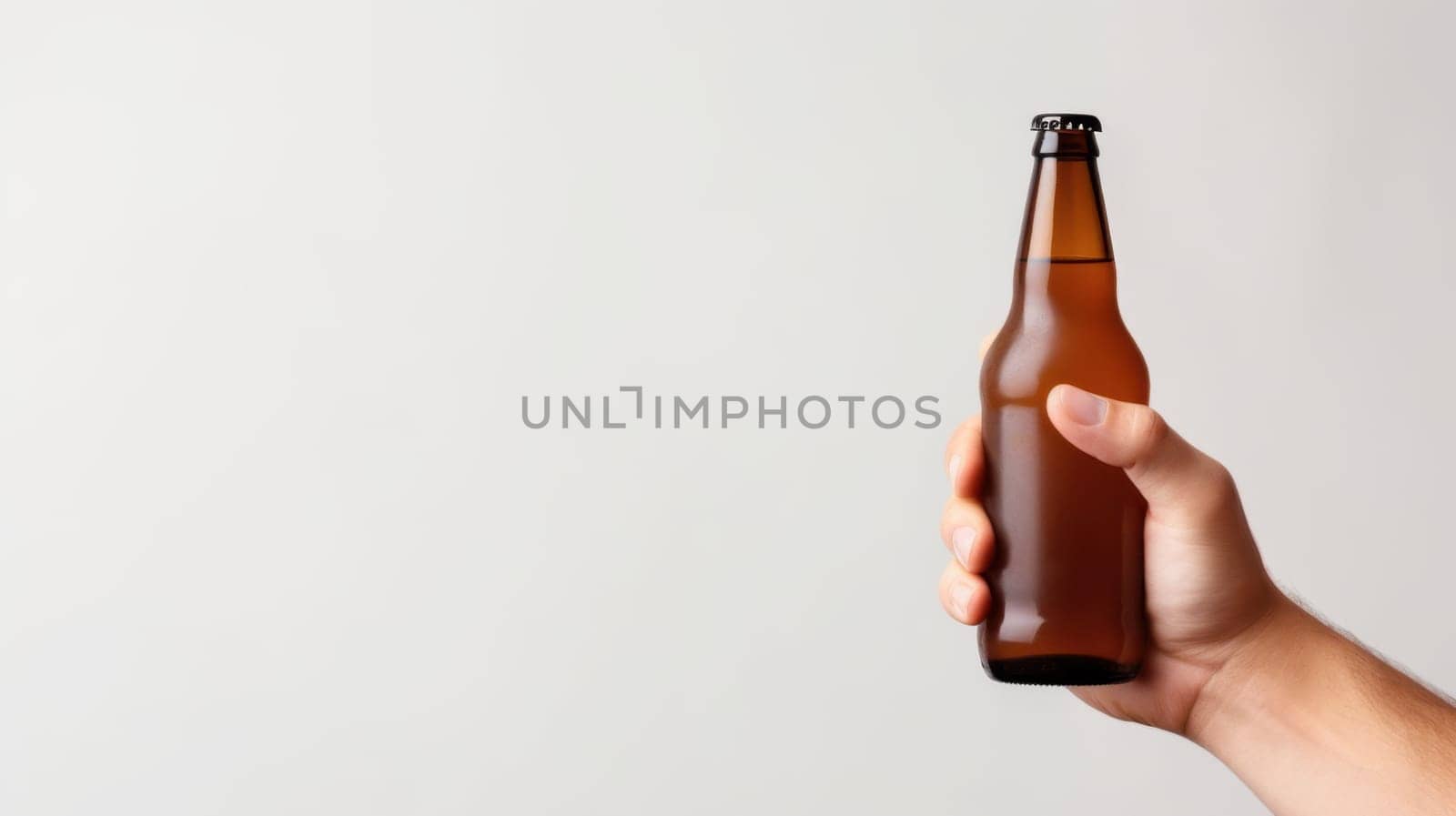 A hand is prominently holding a brown beer bottle with a black cap against a clean, white background. The bottle is a standard size, making it perfect for enjoying your favorite beer.