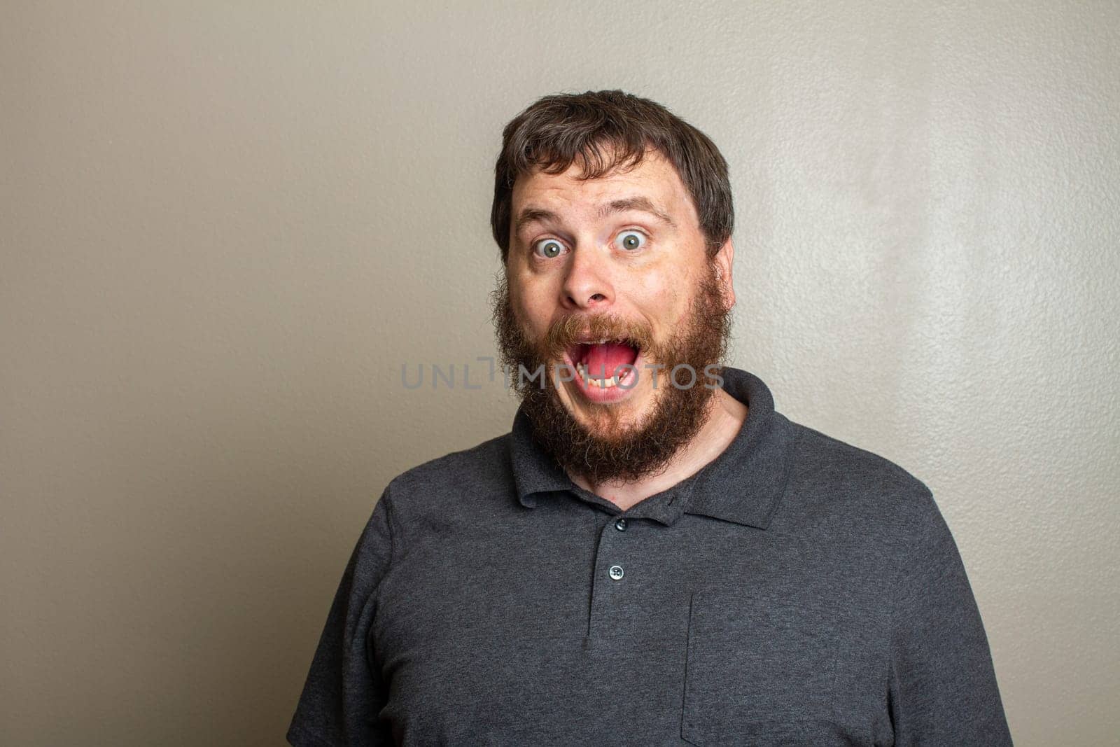 Portrait of a bearded man with mouth wide open, expressing surprise or shock. The neutral background emphasizes his emotional reaction, making the image suitable for humor or astonishment concepts.