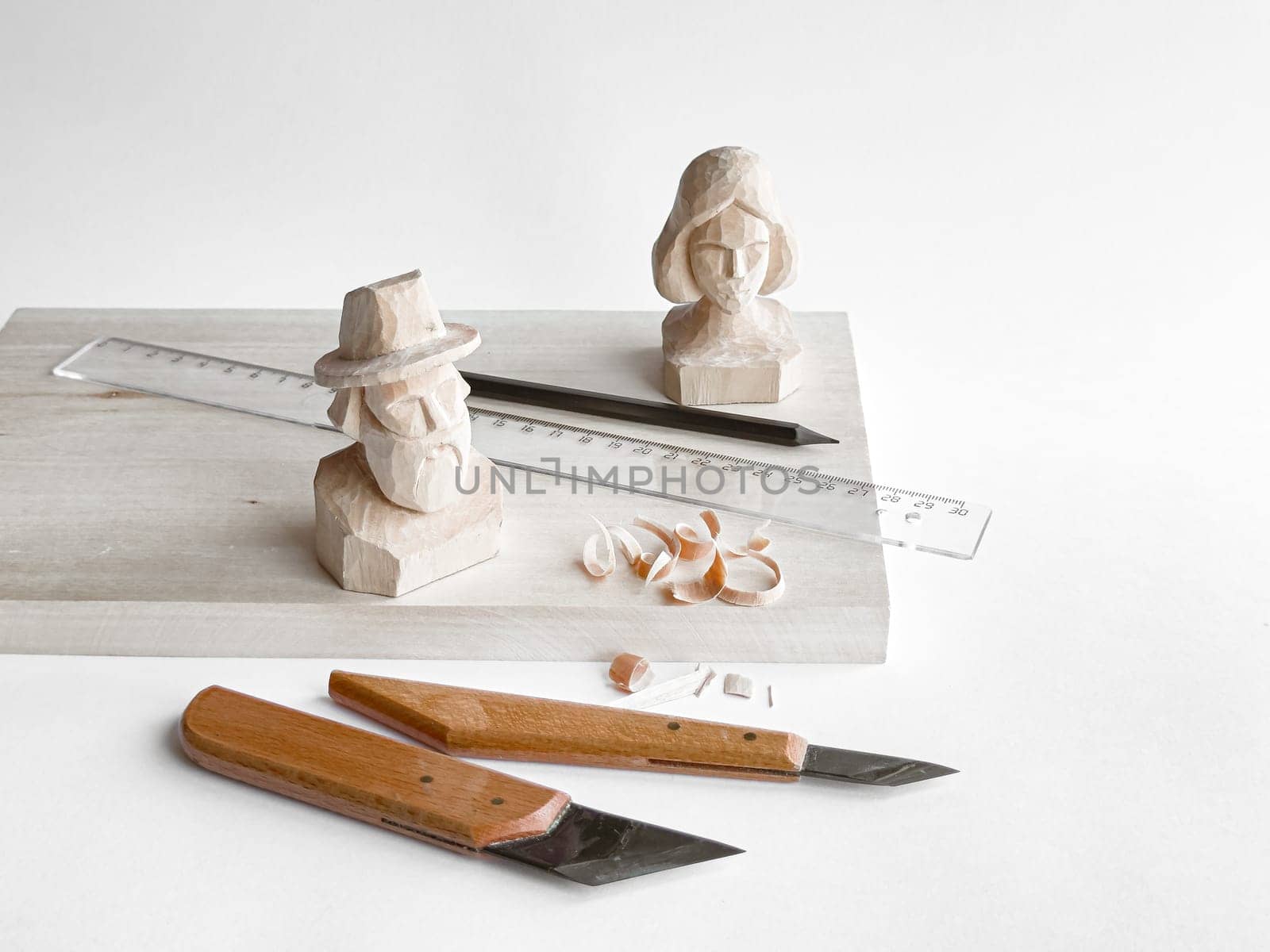 Wood carving tools with handcrafted busts on display board.