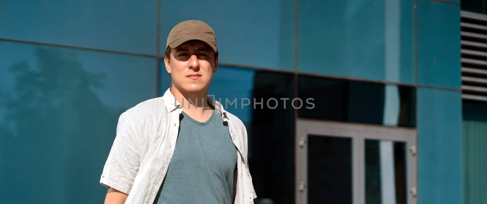 Stylish good looking man in casual clothes against the backdrop of an urban glass building, office, young businessman, entrepreneur walking through a modern area of the city outdoors.