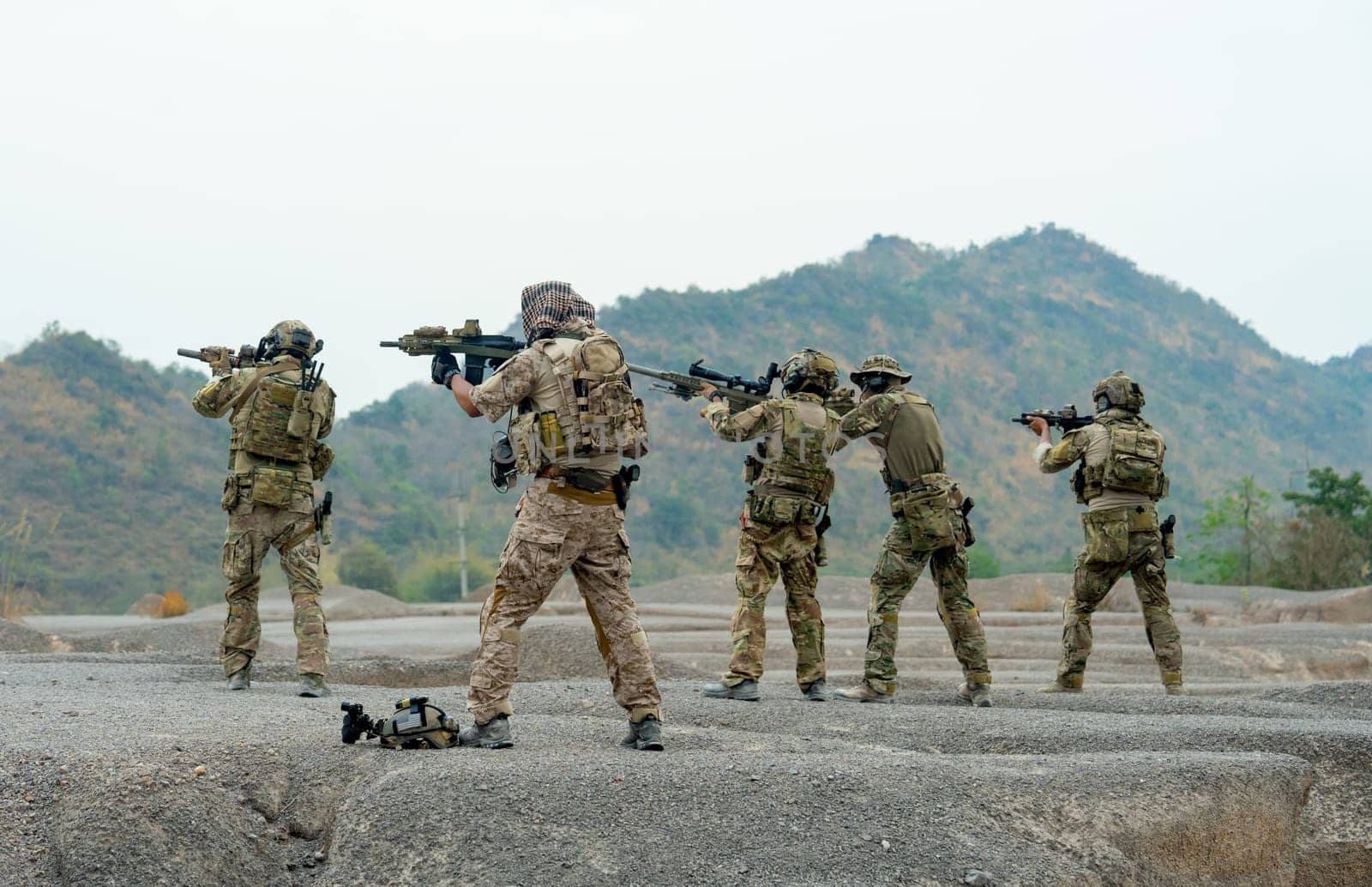 Side view group of military or soldiers stand with point gun to left side to the enemy in area of battlefiled or practice area.