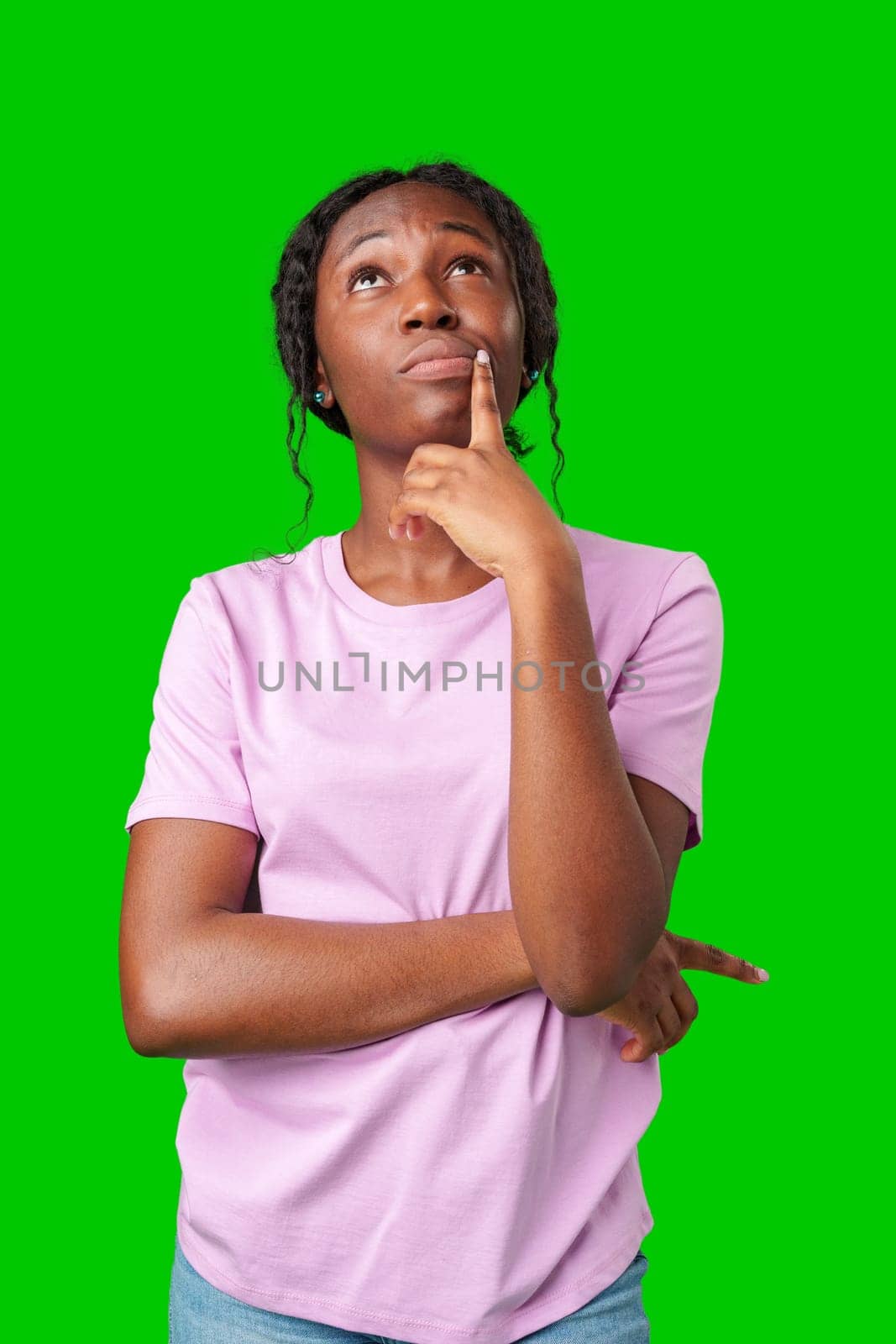 Thoughtful woman pondering in front of a bright green background during a casual moment close up