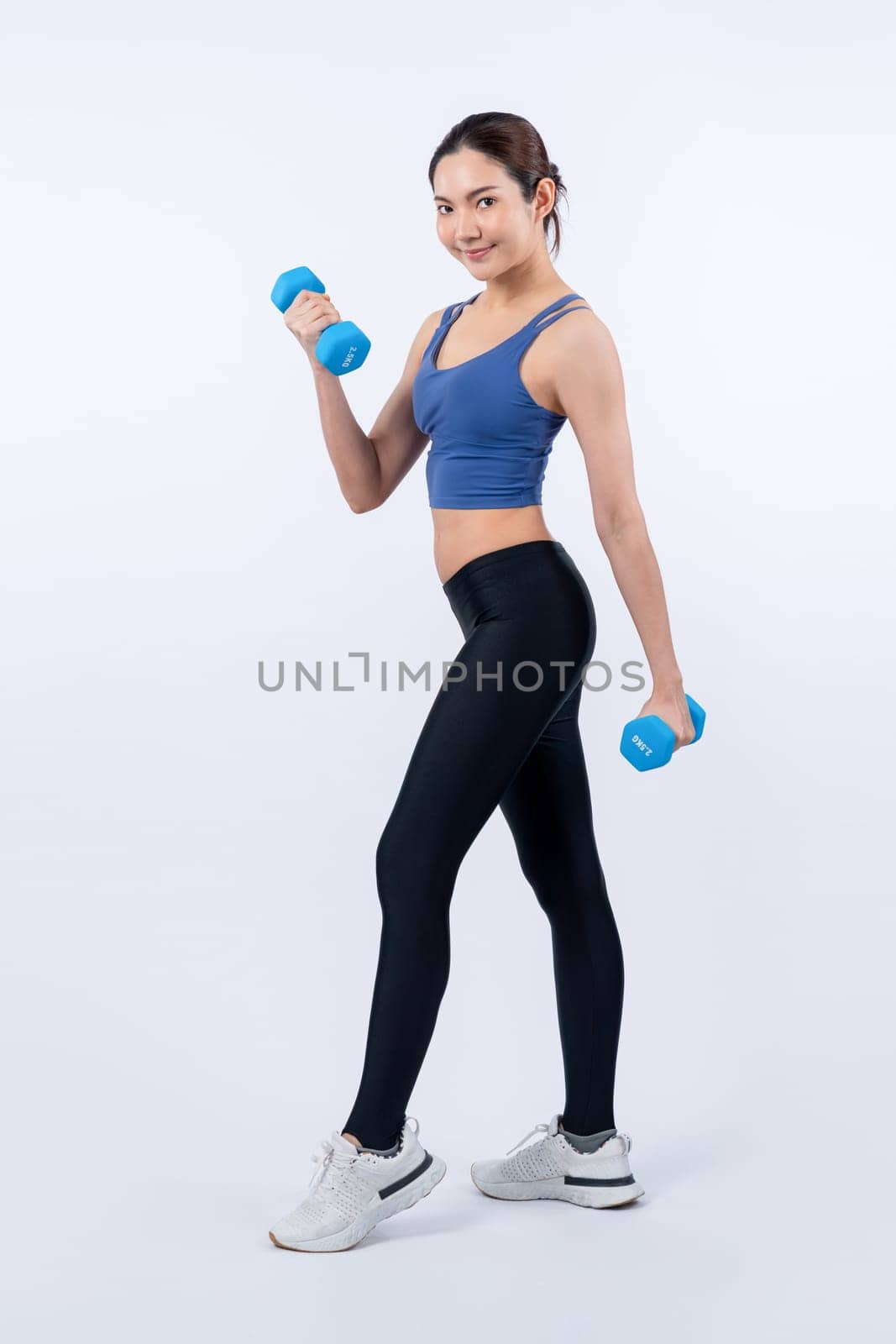 Vigorous energetic woman doing dumbbell weight lifting exercise on isolated background. Young athletic asian woman strength and endurance training session as body workout routine.