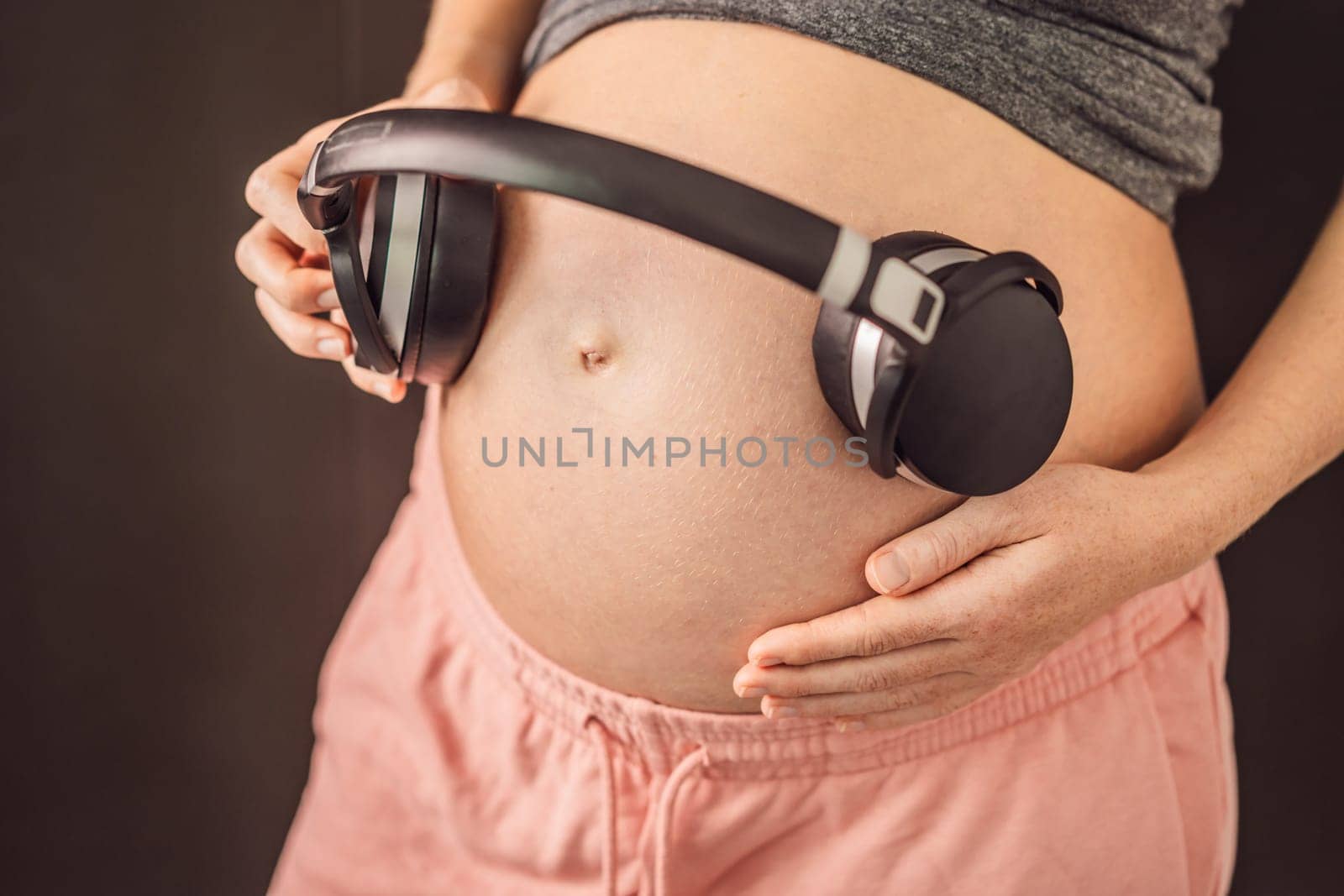 Melodies in the womb: Headphones placed on a pregnant belly, bonding through music, a heartwarming connection between mother and baby by galitskaya