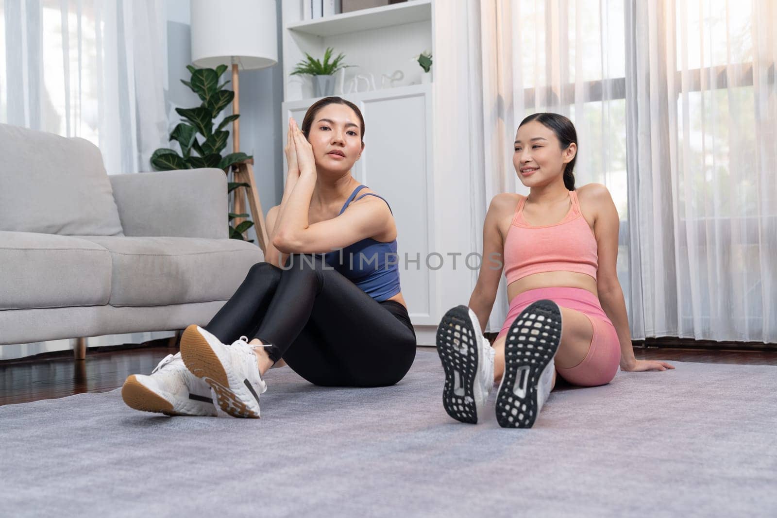 Asian woman in sportswear with her trainer or workout buddy, smiling and posing cheerful gesture. Home workout training or exercise fitness lifestyle in pursuit of healthy lifestyle. Vigorous