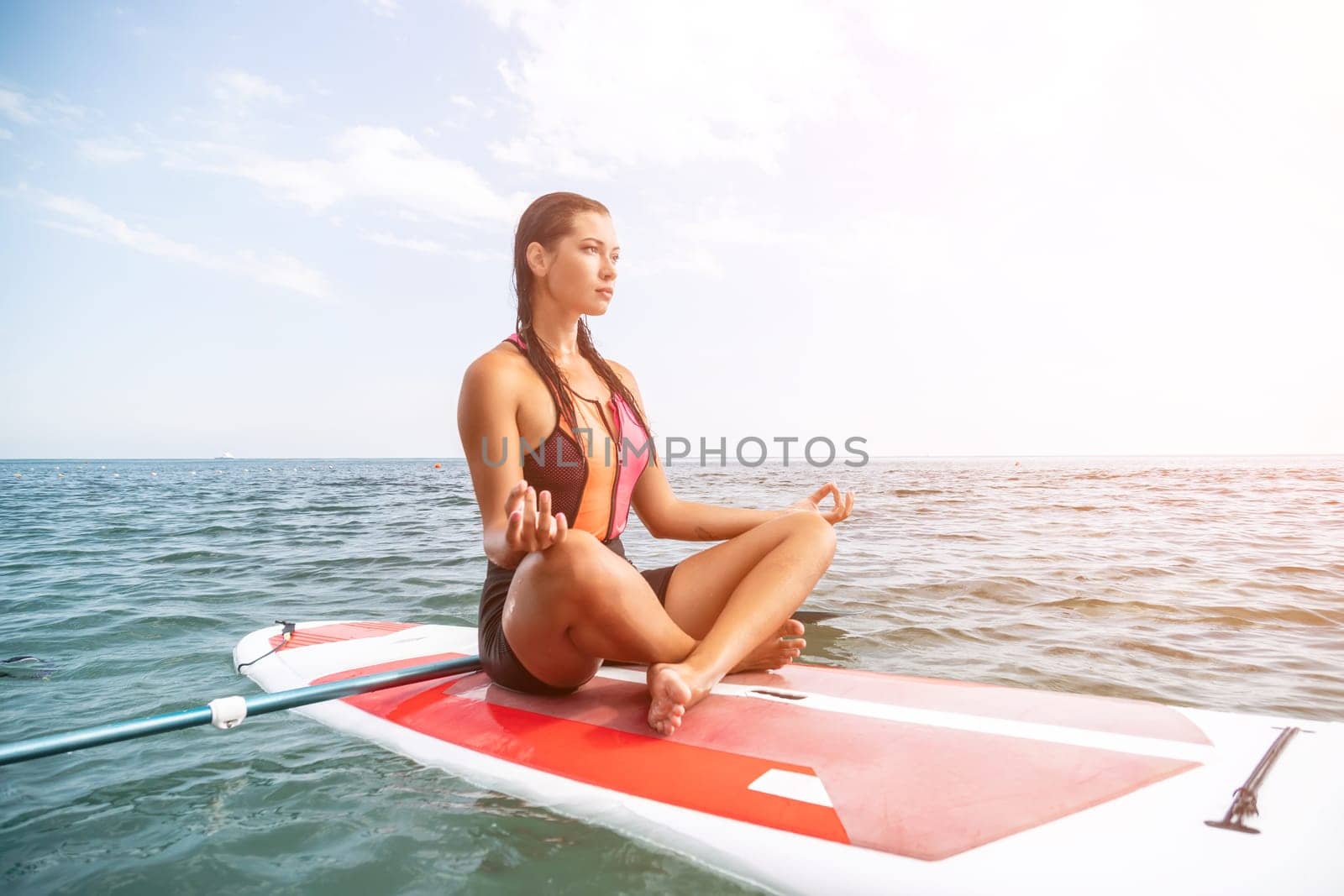 Woman sup yoga. Happy young sporty woman practising yoga pilates on paddle sup surfboard. Female stretching doing workout on sea water. Modern individual female outdoor summer sport activity