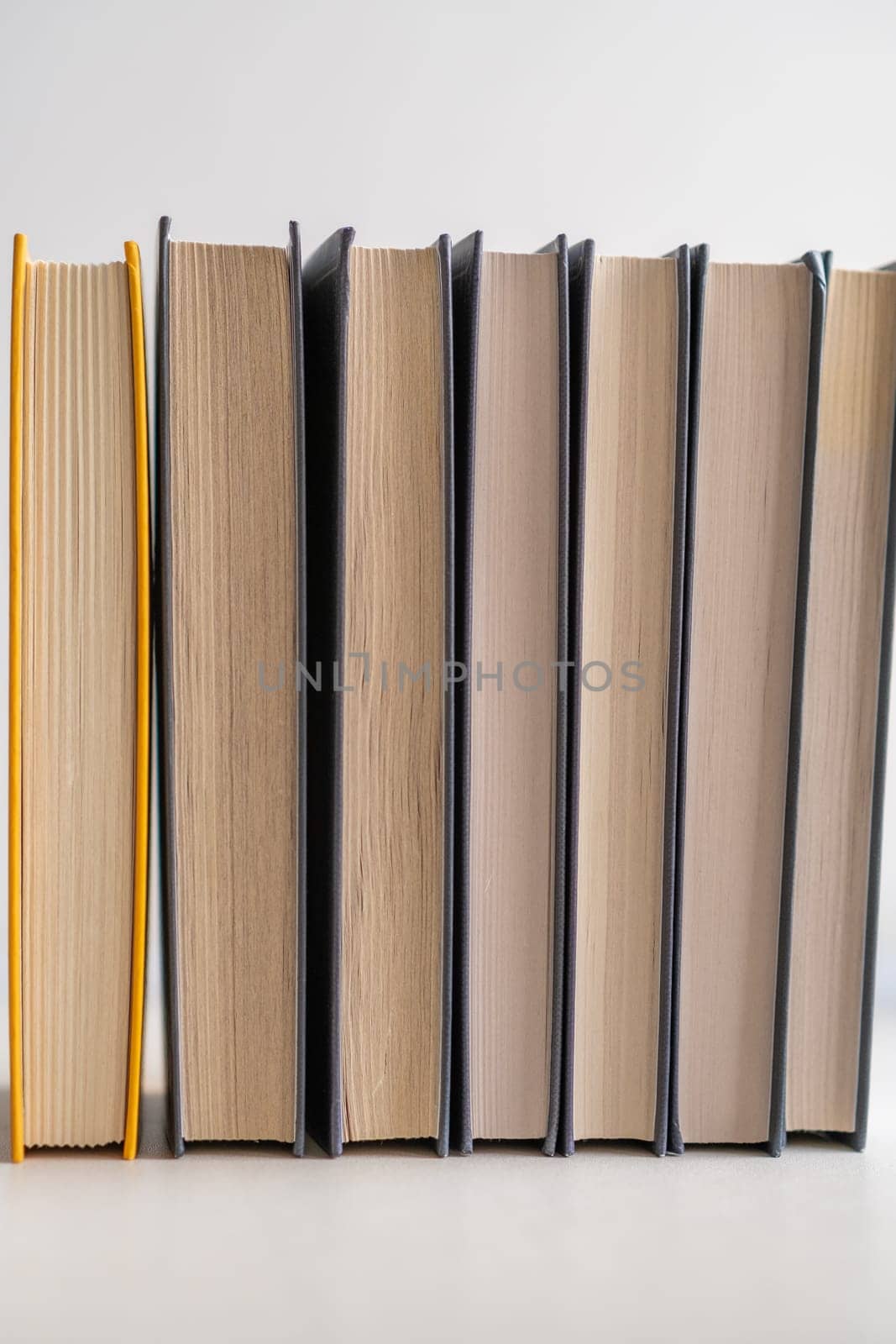 Stack of books on a white background. One book is yellow. Book reading and learning concept.