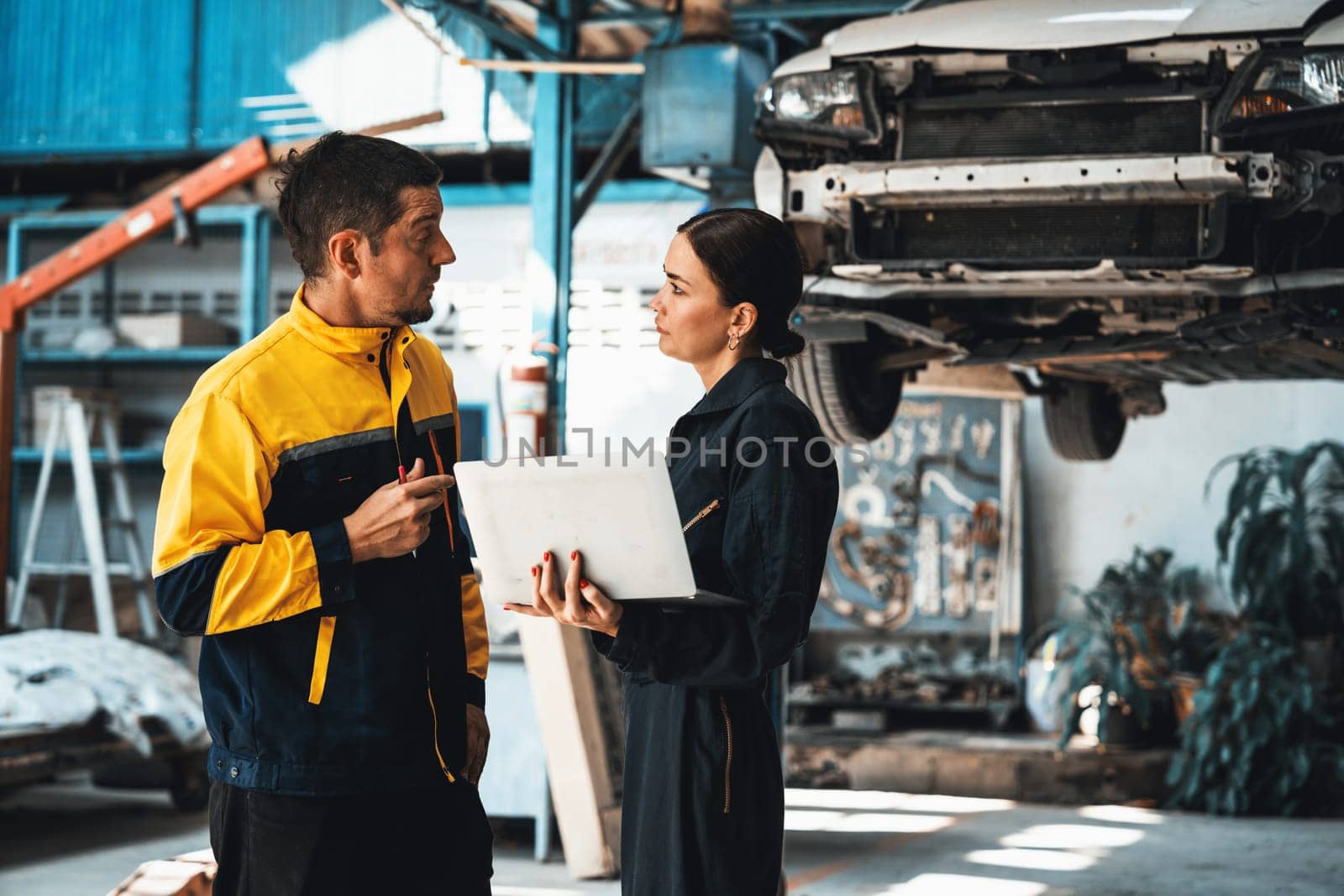 Two vehicle mechanic working together, conduct car inspection with laptop. Automotive service technician in uniform carefully make diagnostic troubleshooting to identify error. oxus