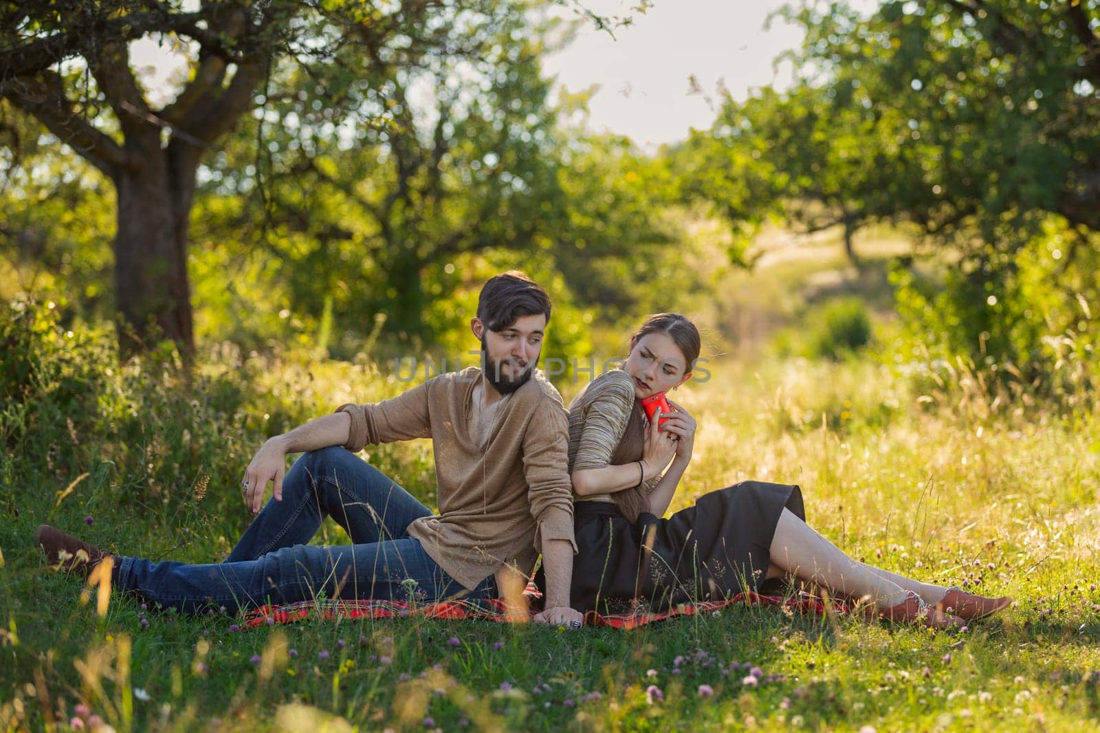 Young couple in nature, a girl with a phone is texting someone