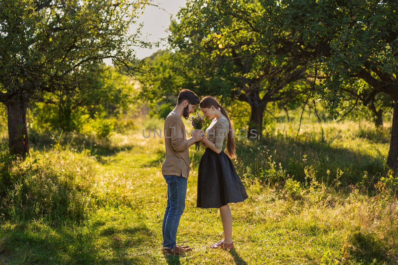 couple in nature with wildflowers, smelling a bouquet