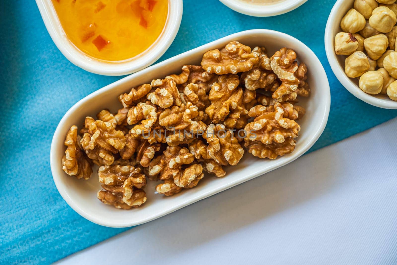 Pile of walnuts in a white porcelain bowl on the breakfast table by Sonat