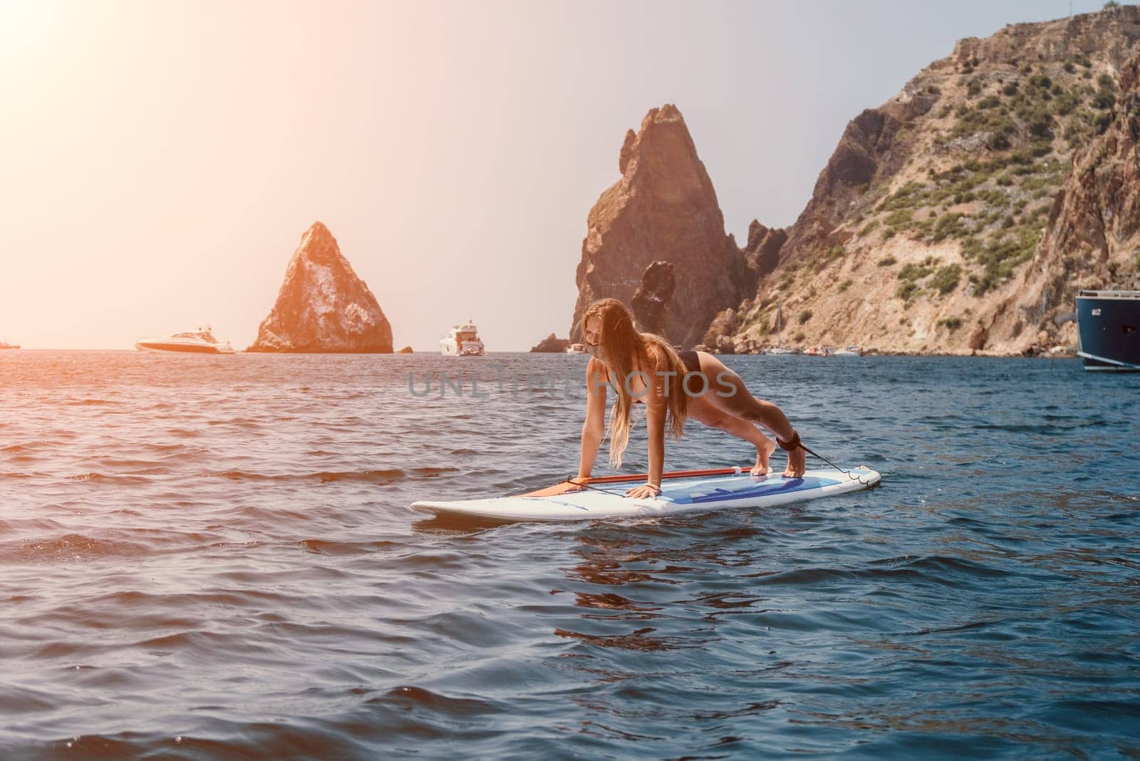 Woman sea sup. Close up portrait of happy young caucasian woman with long hair looking at camera and smiling. Cute woman portrait in bikini posing on sup board in the sea by panophotograph