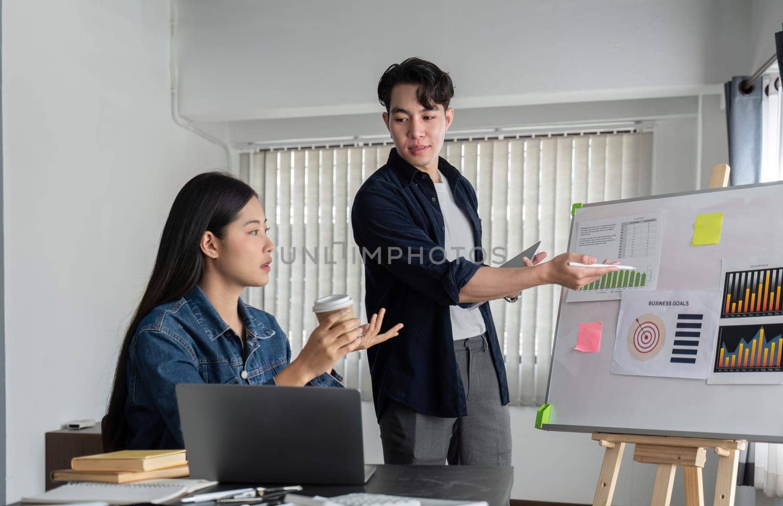 Young businessman explains work plan in meeting to teammates in conference room..