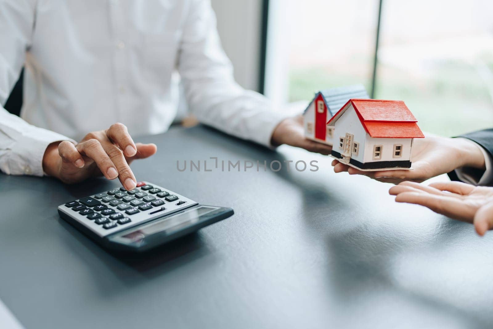 Guarantee, mortgage, contract, contract, signed, real estate agent or bank officer holding a calculator, submits a bid with a customer to buy a home before signing to make a deal by Manastrong