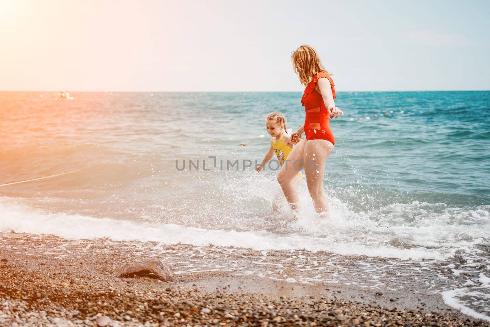 Happy loving family mother and daughter having fun together on the beach. Mum playing with her kid in holiday vacation next to the ocean - Family lifestyle and love concept by panophotograph