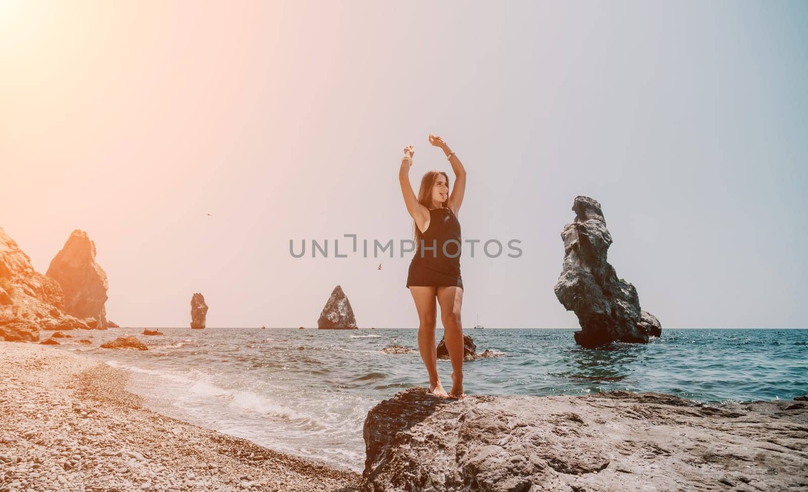 Woman summer travel sea. Happy tourist in hat enjoy taking picture outdoors for memories. Woman traveler posing on the beach at sea surrounded by volcanic mountains, sharing travel adventure journey by panophotograph