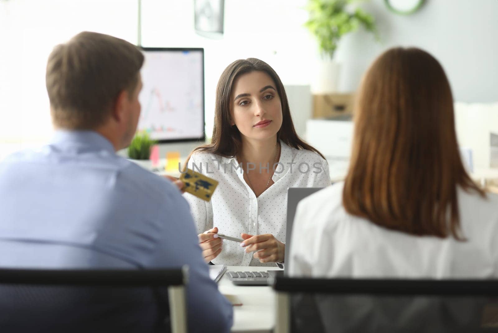 Portrait of joyful businesswoman working at modern workplace with friendly clients. Woman listening attentively customer wishes. Biz negotiations concept