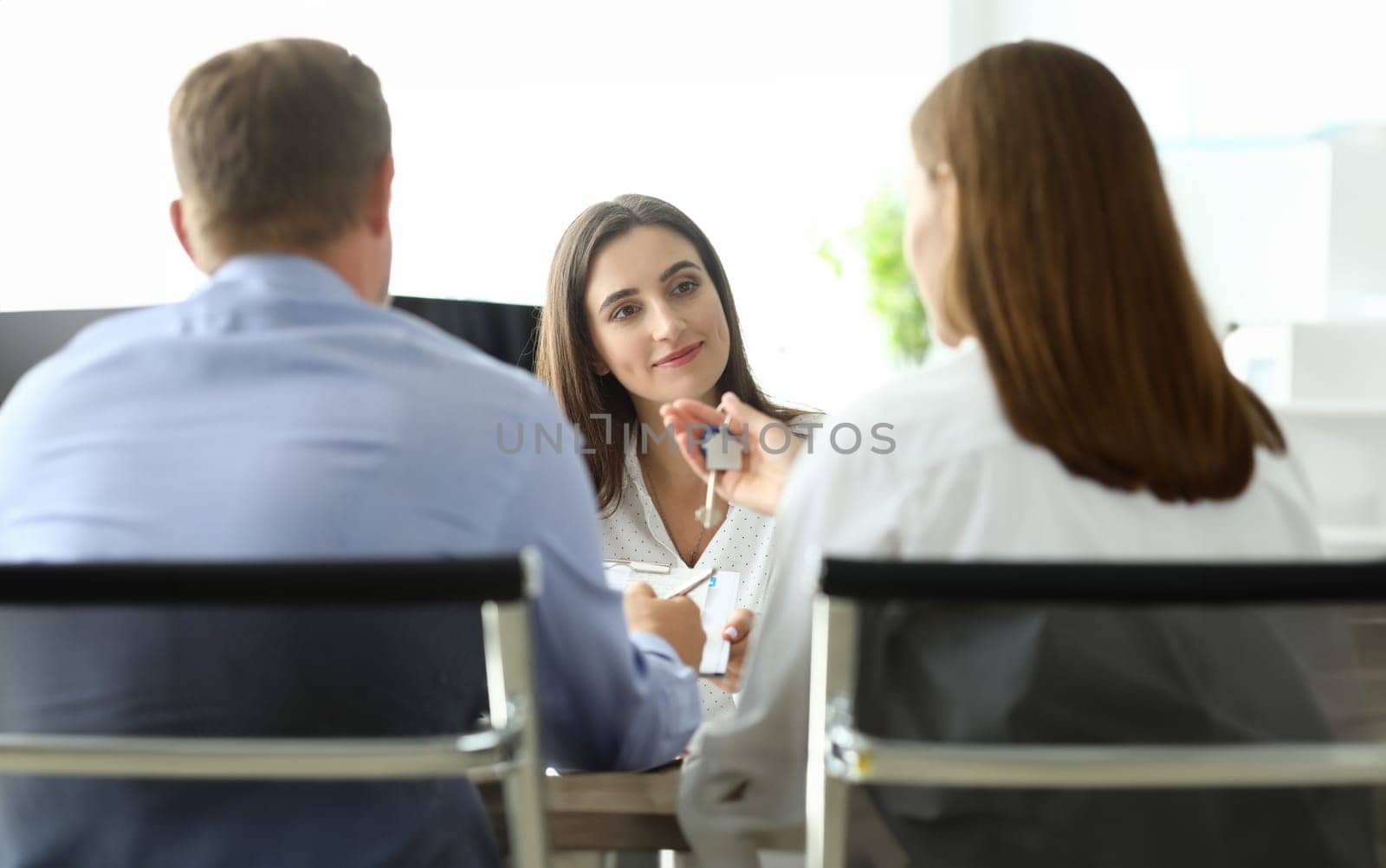 Portrait of businesswoman looking at client with gladness. Woman owner holding house keys. Conclusion of profitable agreement. Real estate market concept