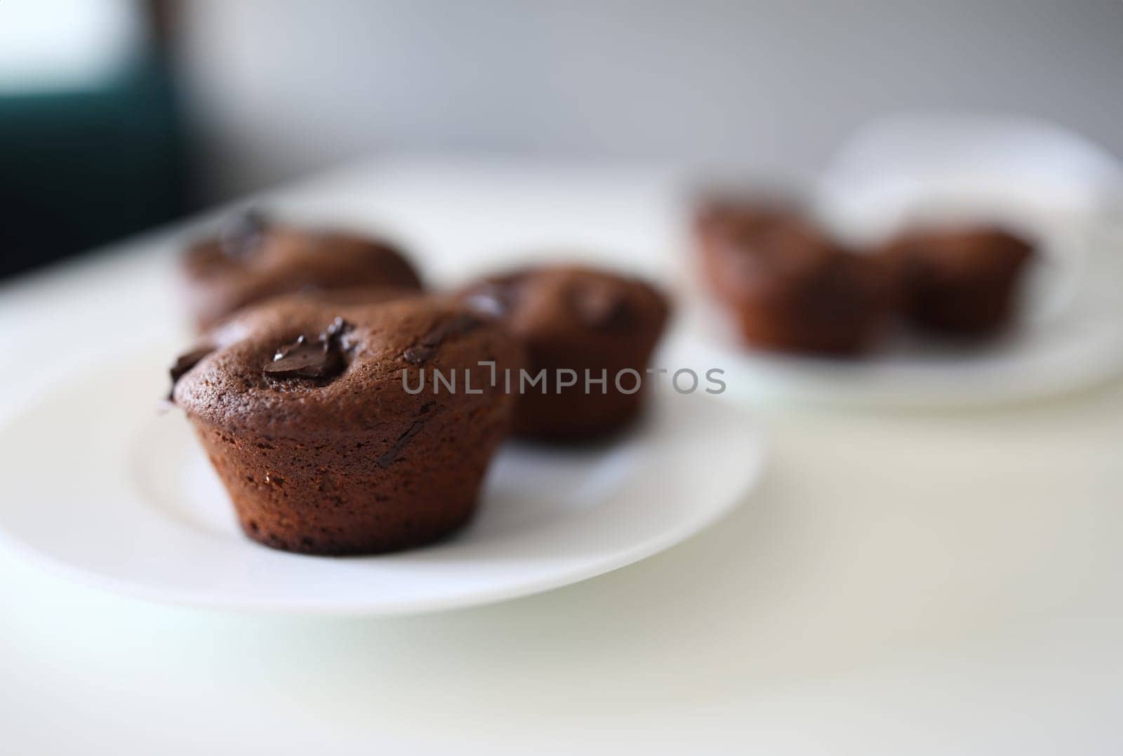 Close-up of tasty dessert for tea or coffee. Chocolate brownies with cocoa stuffing on white plate. Homemade cupcakes with crispy top. Bakery and confectionery concept