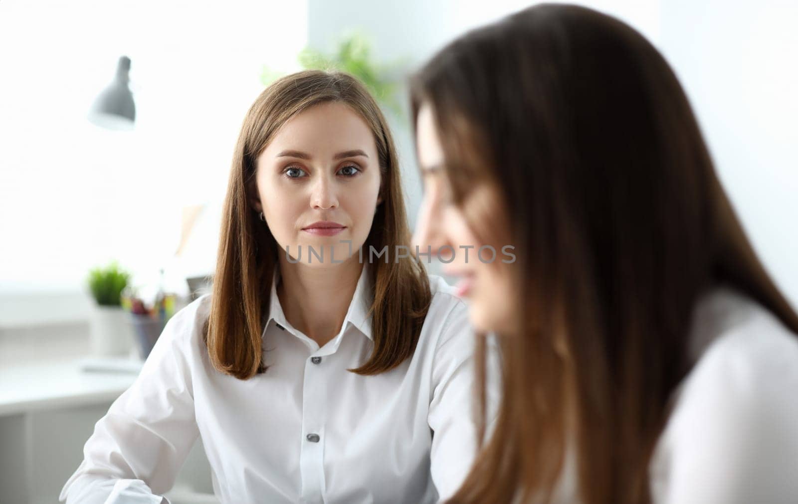 Portrait of smart businesswoman sitting at modern workplace and having silent question in pretty eyes. Gorgeous woman talking with colleague. Accounting office concept