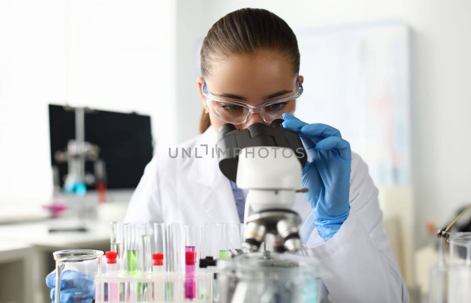 Portrait of scientist examining sample under microscope. Experienced lab assistant using special equipments. Laboratory interior on background. Chemical experiments concept