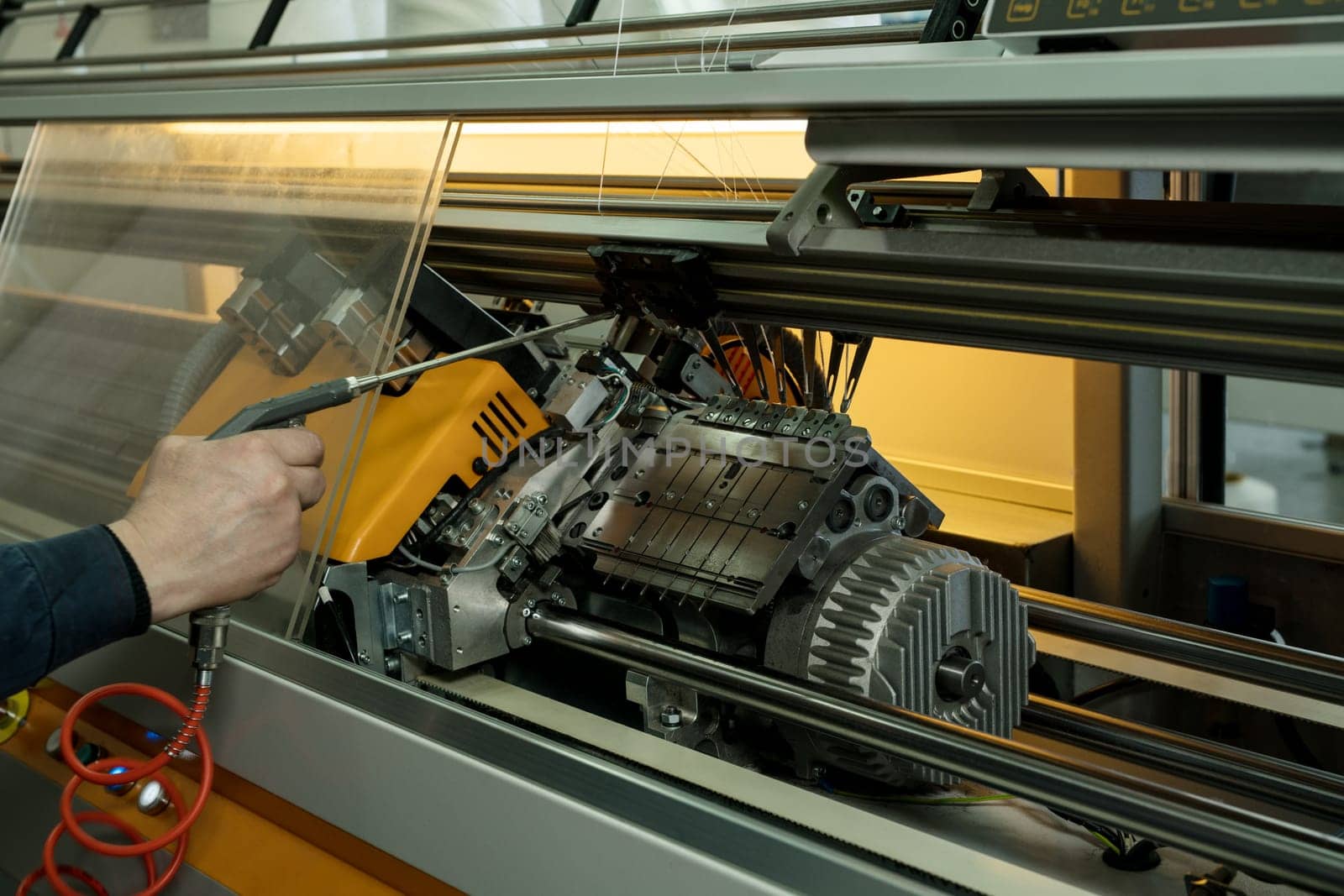 Serviceman setting up the knitting machine close up cropped view