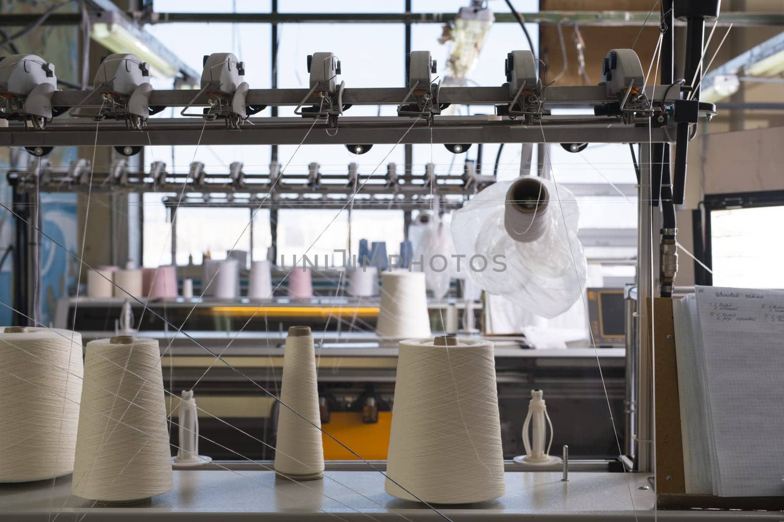 Big spools with white thread at rewinding machine view