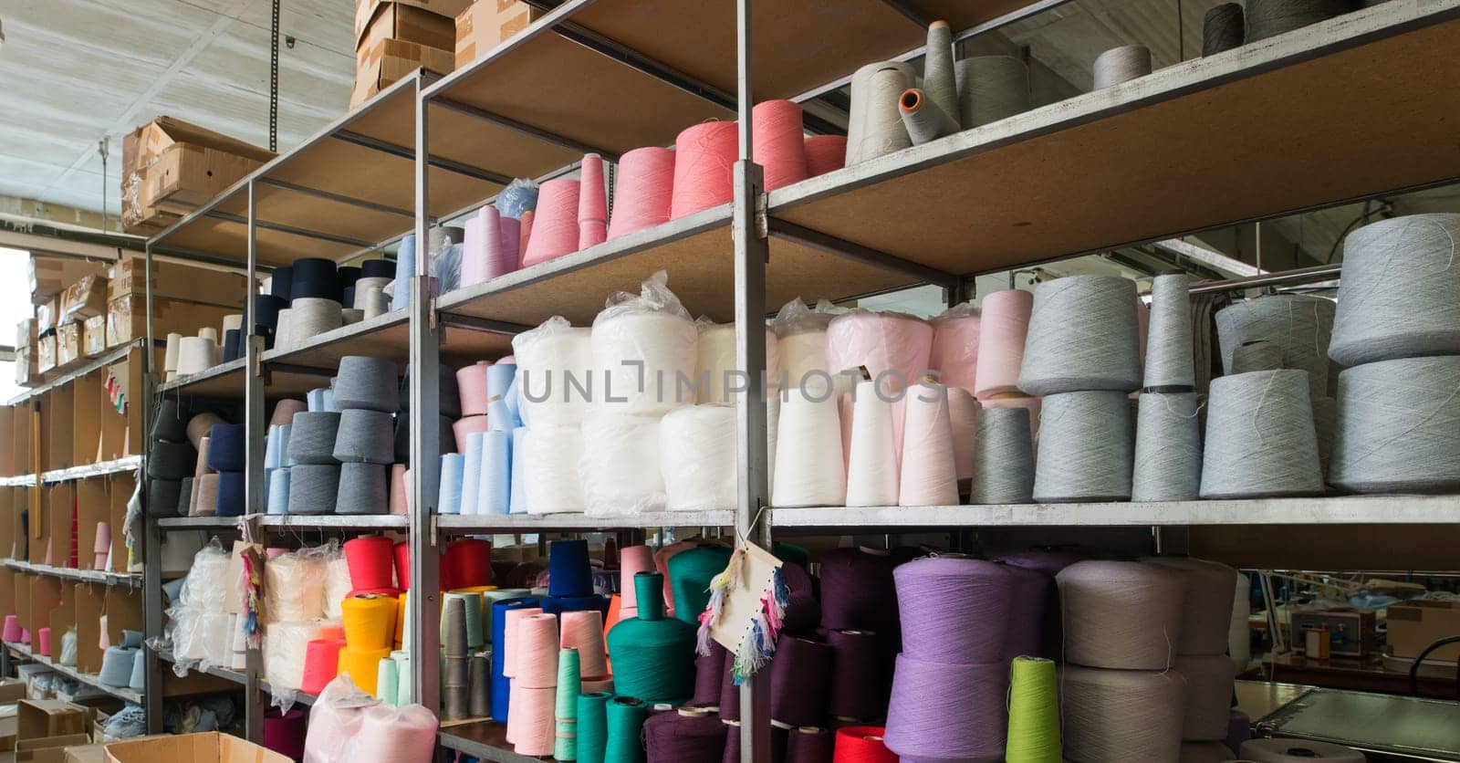 Color thread spools kept on shelves at knitting factory shot