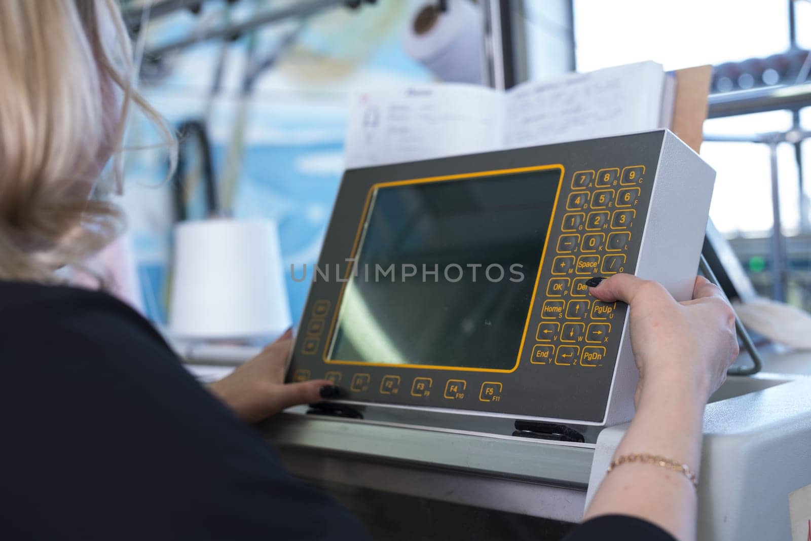Female operator setting programme at knitting machine control panel view