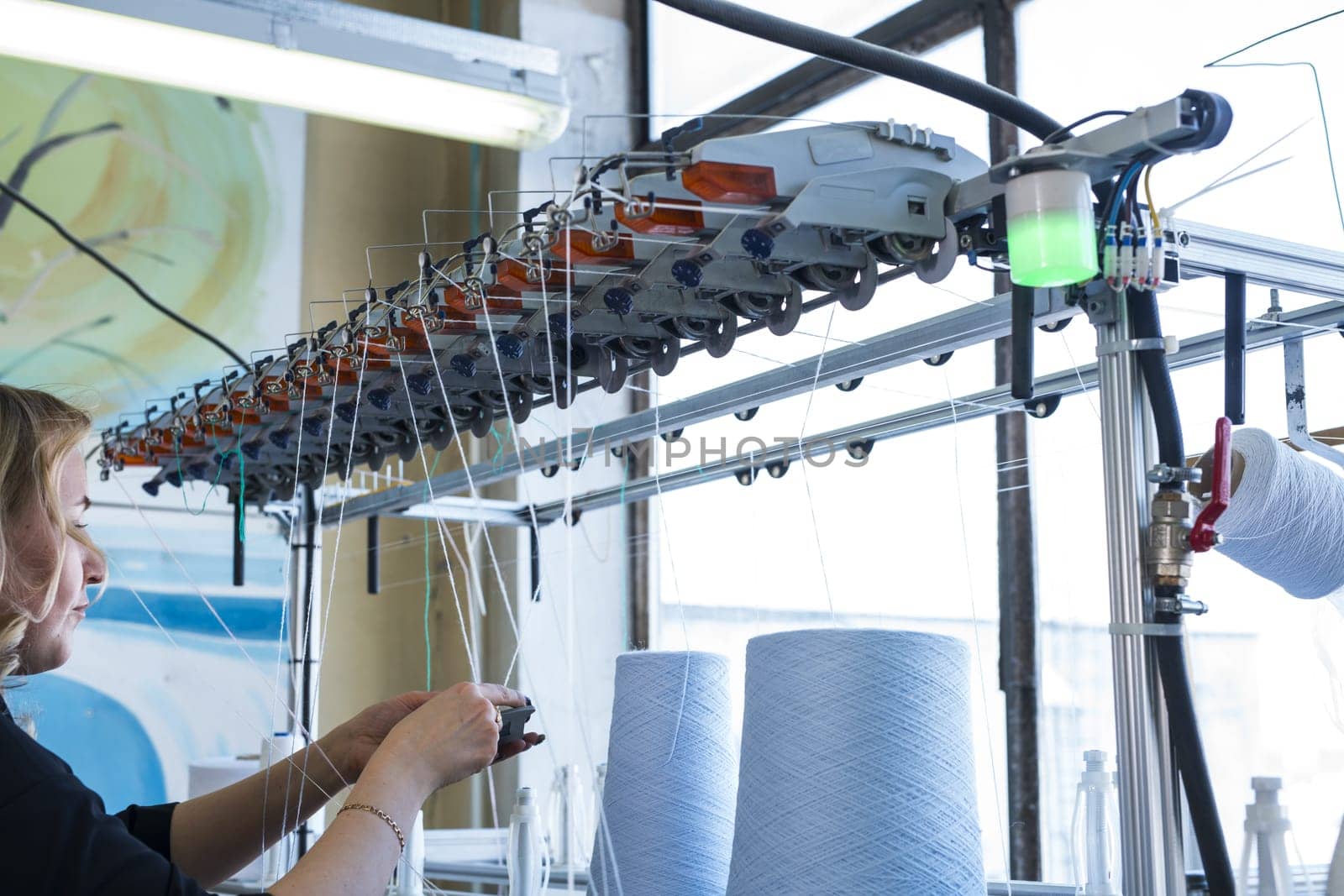 Female operator working at thread rewinding machine cropped view