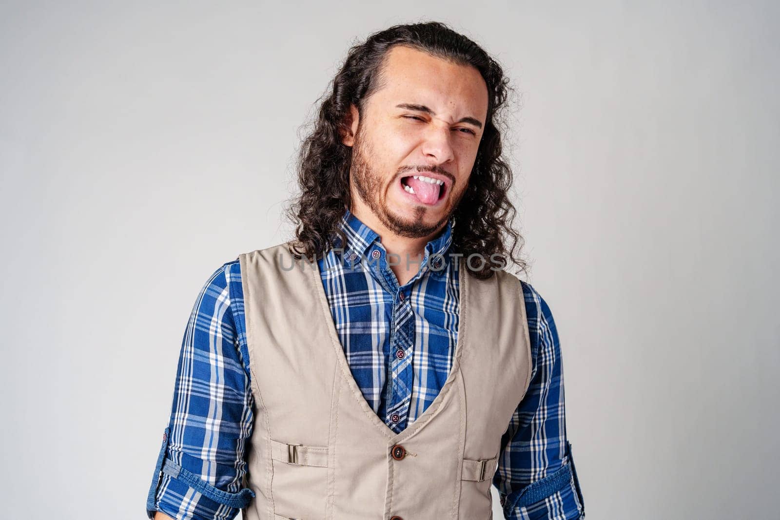Man making a silly face with tongue out in casual attire against a neutral background close up