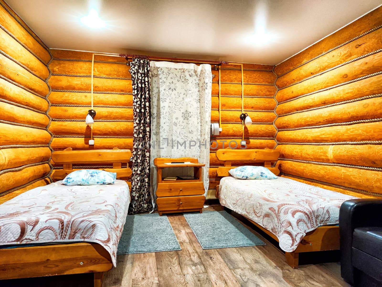 The cabin showcases a warm wooden interior with two neatly made single beds and soft textiles, creating a tranquil accommodation space.