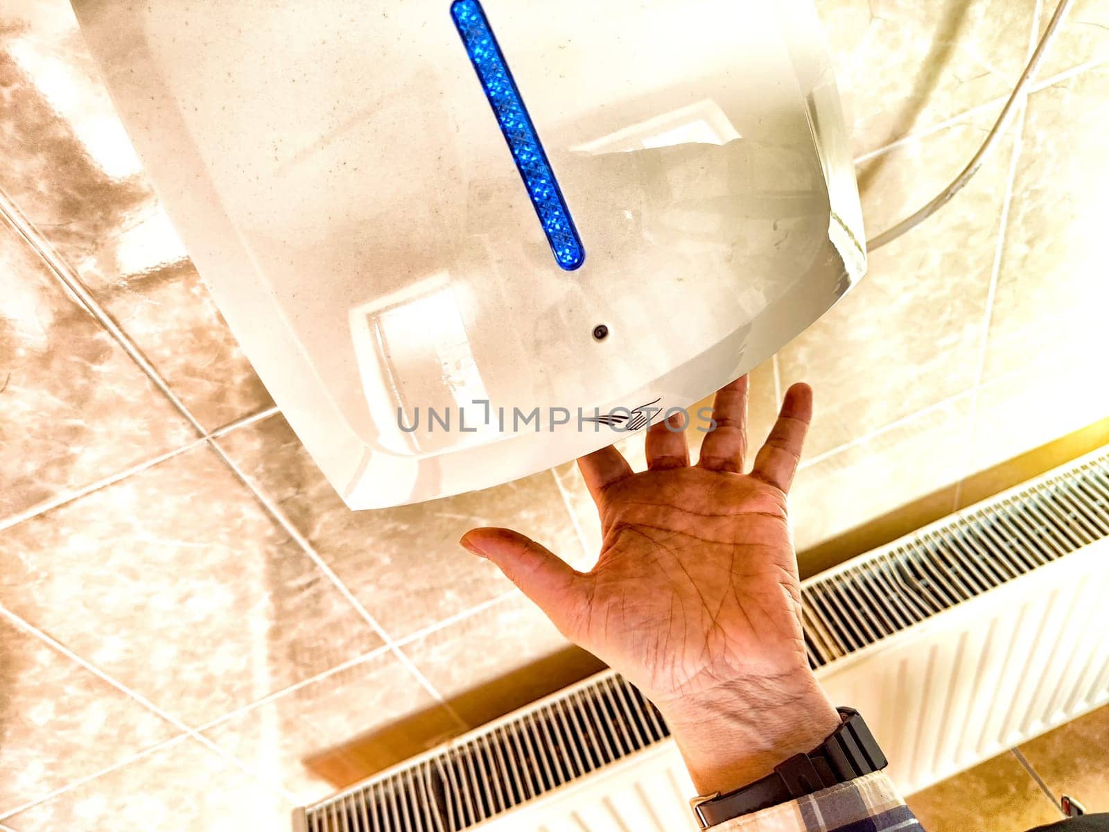 A person places their hand under a hand dryer in restroom, utilizing modern technology for quick drying