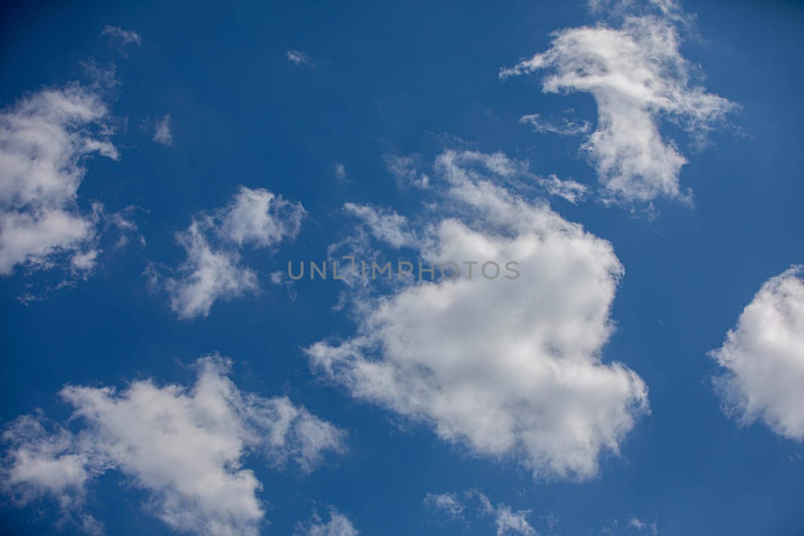 A beautifully serene view of fluffy white clouds peacefully drifting across a bright blue sky on a sunny day