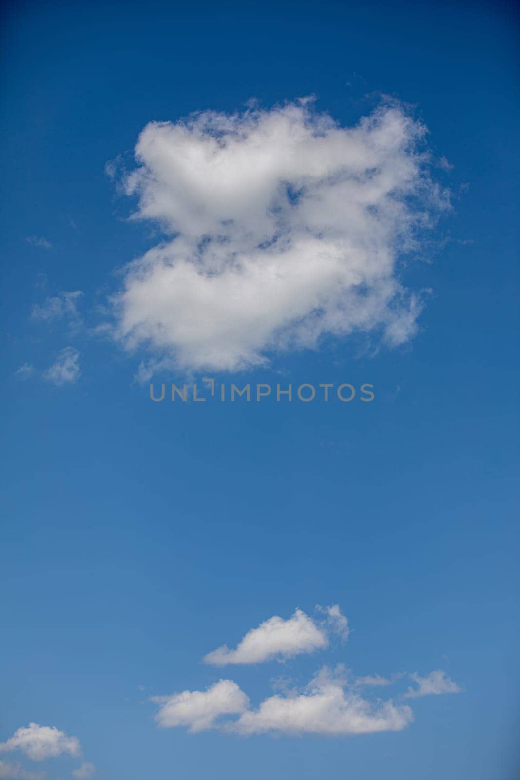 A calming view of fluffy white clouds drifting in a vivid blue sky, evoking a deep sense of tranquility