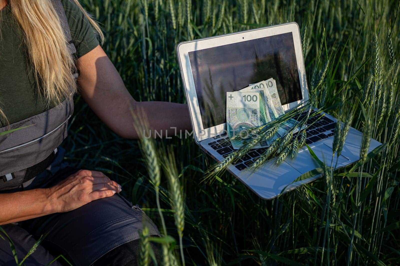 A farmer using a laptop in a lush green field, showcasing the blend of agriculture and modern technology