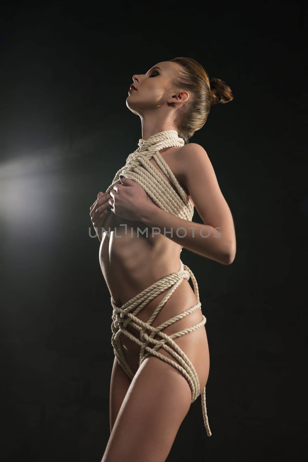 Nude woman in the nude tied up with rope cropped view