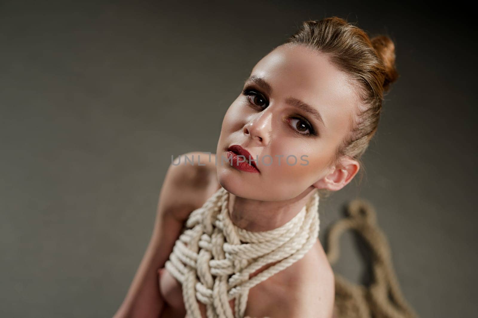 Beautiful woman in the nude tied up with rope high angle portrait
