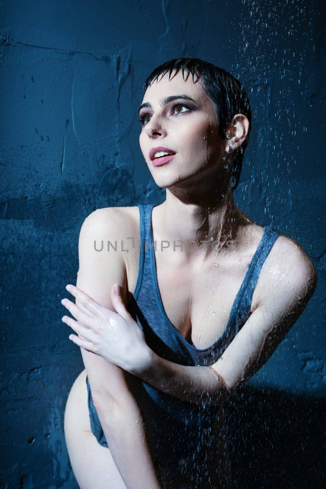 Beautiful brunette in sexy t-shirt having shower in dark room portrait